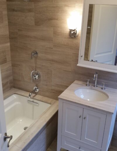 Modern bathroom interior with a bathtub, wall-mounted fixtures, and a single sink vanity.