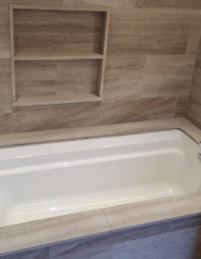 Modern bathroom interior with a built-in bathtub and tiled walls.