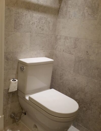 Modern bathroom interior with a white toilet against a tiled wall.