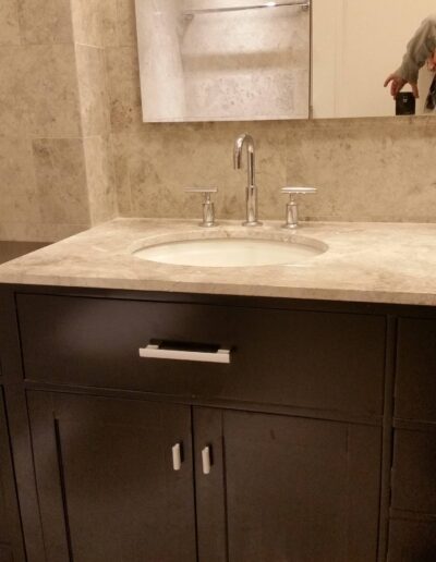 A modern bathroom vanity with a built-in sink, marble countertop, and dark wood cabinets.