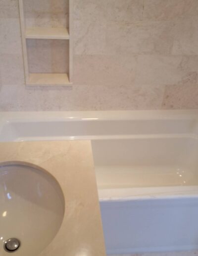 A clean, modern bathroom with a white bathtub and matching tiles.