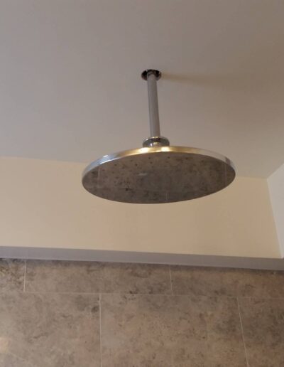 A modern rain shower head installed on a bathroom ceiling.