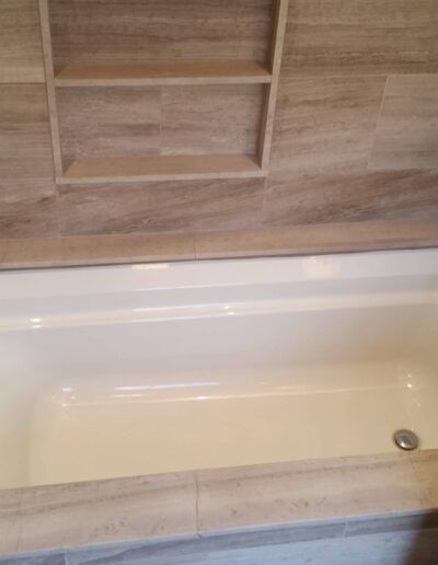 A clean, empty built-in bathtub with surrounding tile work and mounted faucets.