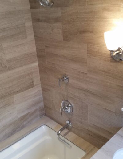 Modern bathroom with beige tile wall, built-in bathtub, and overhead shower.