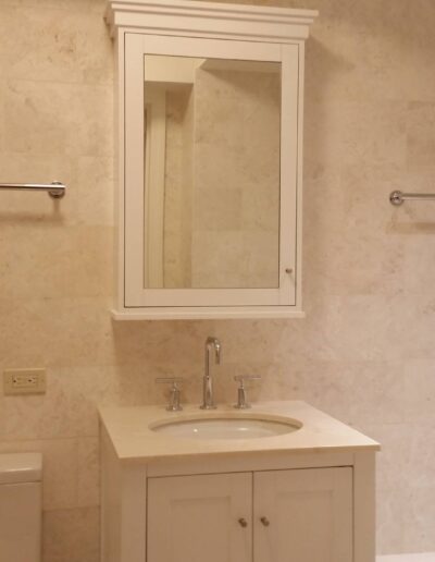 Modern bathroom interior with beige tiles, featuring a sink vanity with a mirror, a toilet, and towel racks.