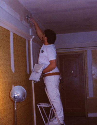 Person painting a wall in a hallway.