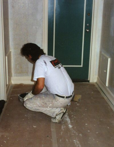 Person kneeling on the floor while working on home renovation.