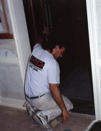 A person wearing a t-shirt with the word "prado" on the back is kneeling while working on a home construction site.