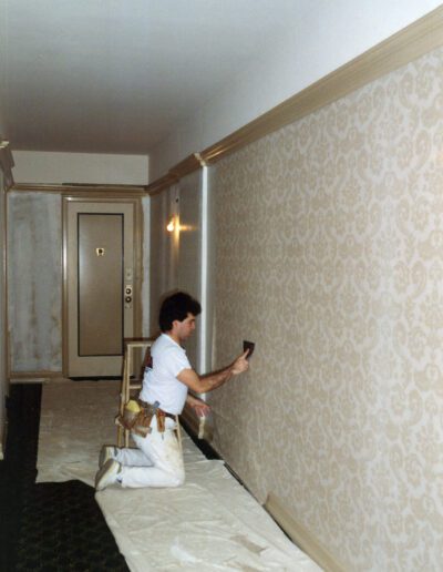 A person applying wallpaper in a corridor.