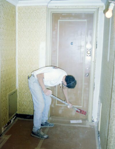 Man painting a hallway floor with a roller.