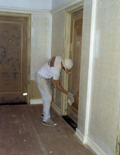 Worker sanding a door frame during a home renovation.