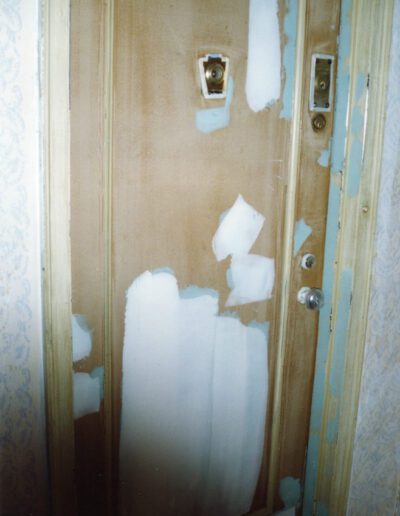 A weathered door with peeling light blue paint and visible signs of wear.