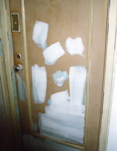 A door partially stripped of paint, with patches where paint has been removed, indicating renovation or repair work in progress.