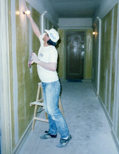 Person applying wallpaper in a hallway.