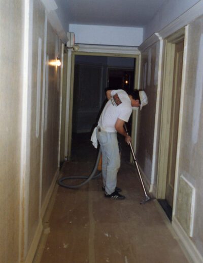 A person vacuuming a hallway.