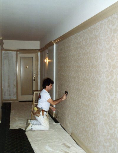 A person applying wallpaper in a corridor.