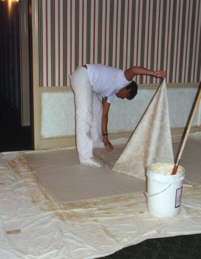 A person preparing a wall for wallpapering.