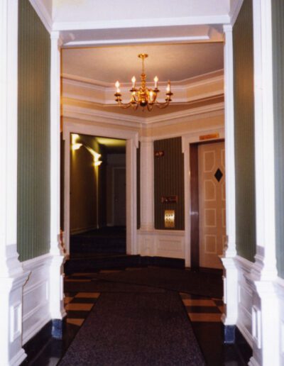 Elegant interior hallway with checkerboard flooring and chandelier.