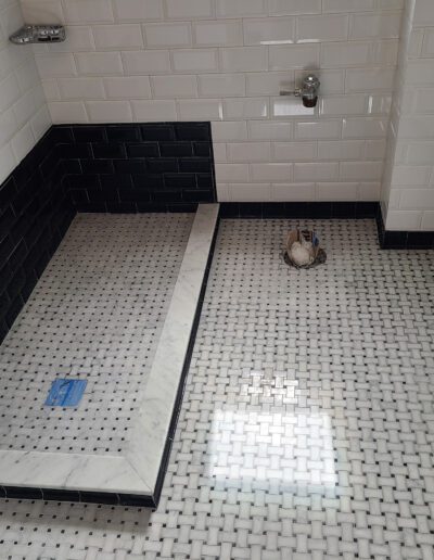 Modern bathroom with a walk-in shower area featuring contrasting white and black tiles.