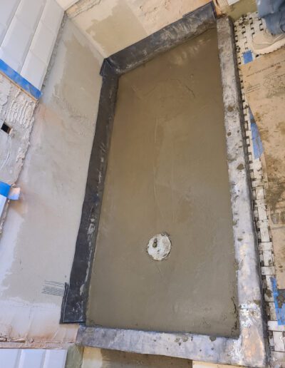 Bathroom under renovation with a freshly applied layer of mortar in a shower pan area.