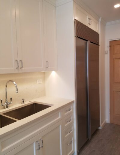 A modern kitchen with white cabinetry, stainless steel appliances, and a double sink.