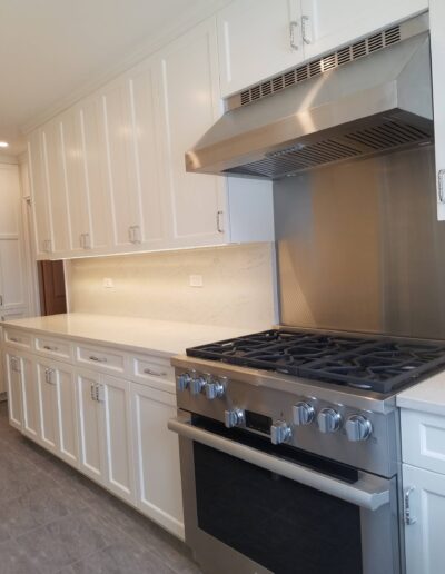 A modern kitchen featuring white cabinetry, stainless steel gas stove, and a range hood.