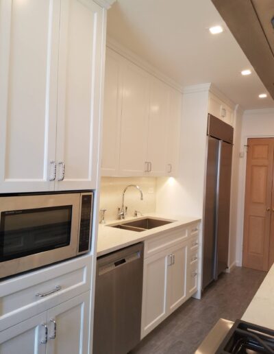 Modern kitchen interior with white cabinets, stainless steel appliances, and quartz countertops.