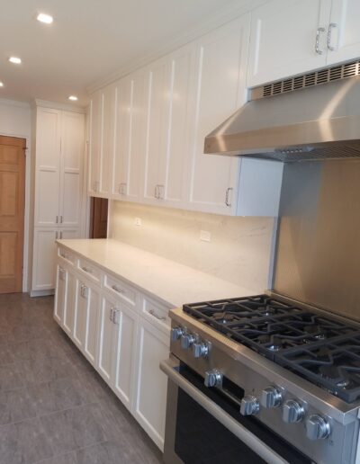 A modern kitchen with white cabinetry, stainless steel appliances, and a gas stove.