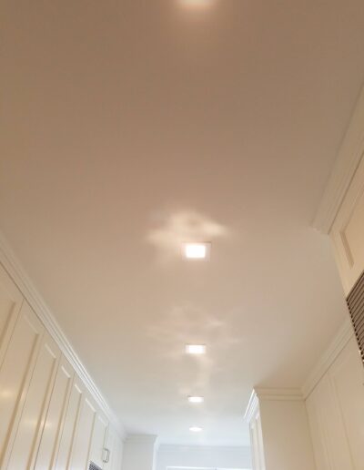 A corridor with a white ceiling fitted with recessed lights.