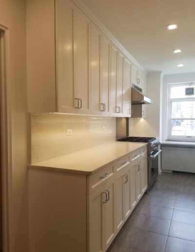 A modern kitchen with white cabinetry, stainless steel appliances, and light-colored countertops.