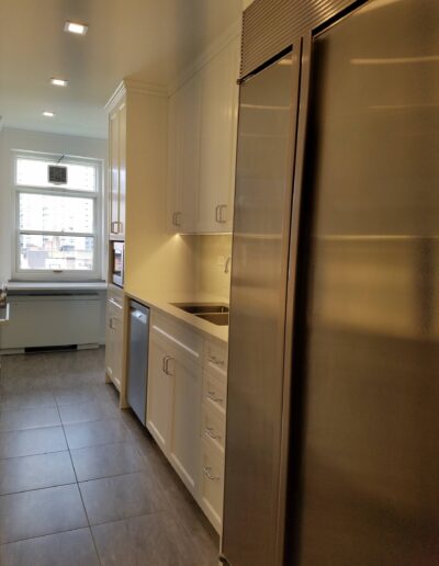 A modern kitchen interior with stainless steel appliances and white cabinetry.