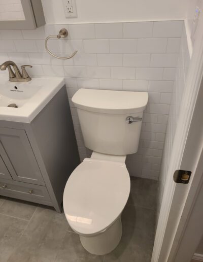 A modern bathroom interior with a white toilet next to a gray vanity and sink.