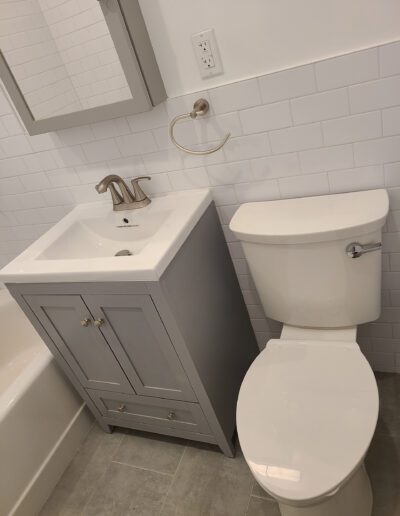 A modern bathroom interior with a white toilet and a gray vanity with a sink.