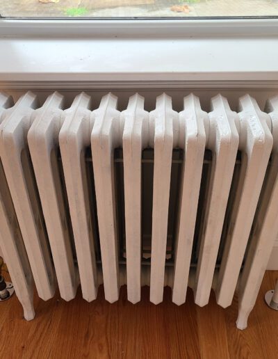 White cast-iron radiator beneath a window.