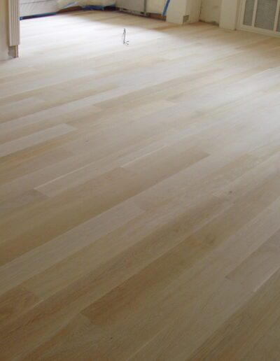 An empty room with a newly installed light wooden floor.