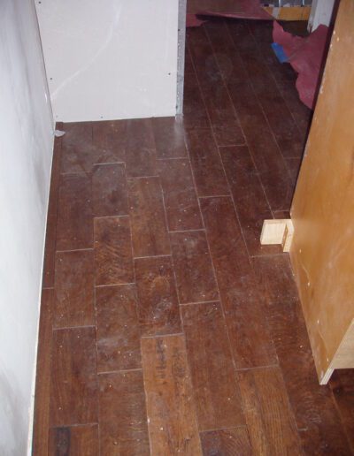 Wooden floor in a room with a visible wooden skirting and a partial view of furniture.