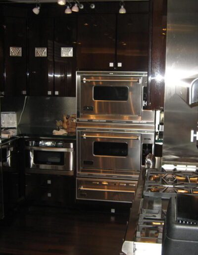 Modern kitchen interior with stainless steel appliances and dark wood cabinets.