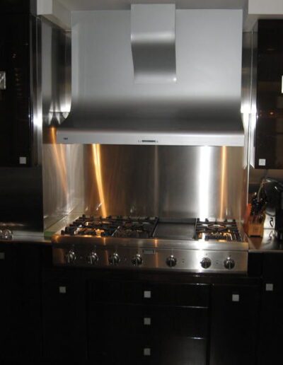 Modern kitchen with stainless steel range hood and appliances.