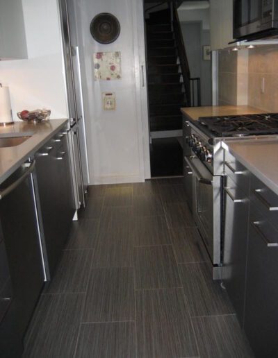 Modern kitchen with stainless steel appliances and dark flooring.