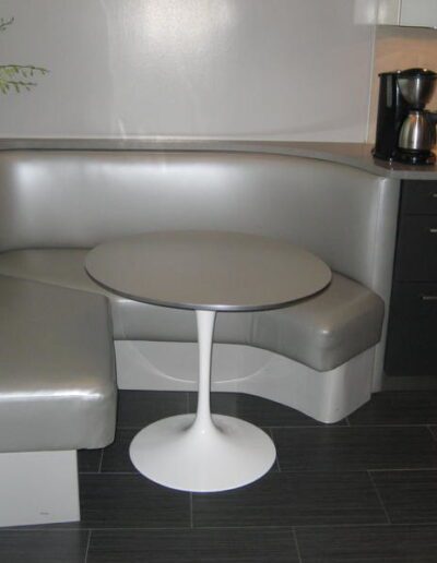 A modern kitchen nook with a round table and l-shaped bench seating.