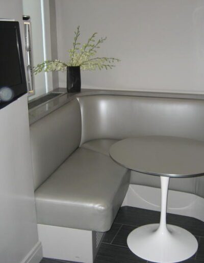 Modern dining nook with l-shaped bench, round table, and wall-mounted television.