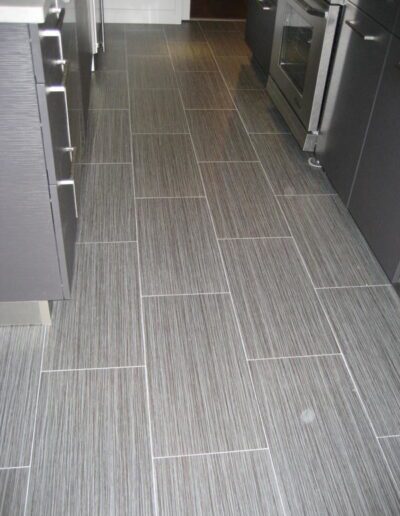 Modern kitchen with gray tile flooring and stainless steel appliances.