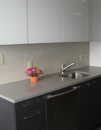 Modern kitchen with gray countertops, white cabinets, and a bouquet of flowers on the counter.