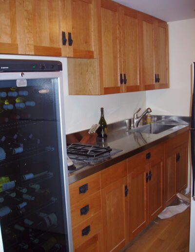 A kitchen corner featuring wooden cabinets, a wine fridge, a gas stove, and a sink.