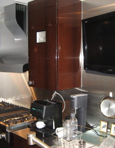 Modern kitchen with stainless steel backsplash, gas stove, and wall-mounted television.