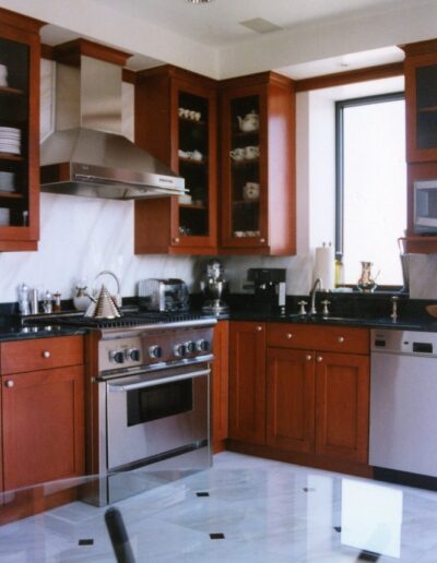 Modern kitchen interior with stainless steel appliances, wooden cabinets, and a tiled floor.