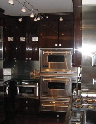 A commercial kitchen with stainless steel appliances including a refrigerator and double ovens.