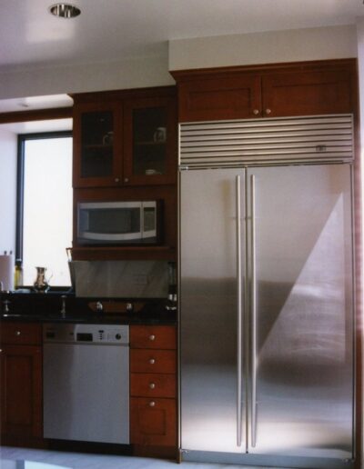 Modern kitchen with stainless steel refrigerator and wooden cabinets.