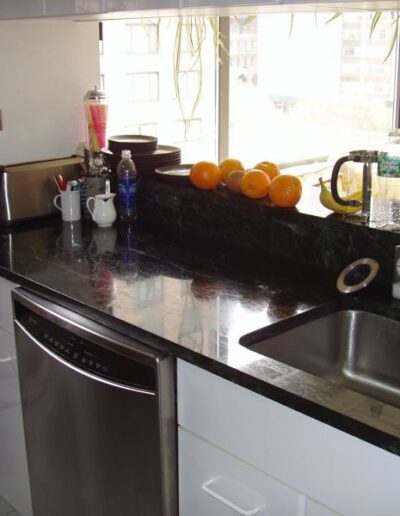 A tidy kitchen counter with appliances and fruit, overlooking a window.