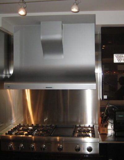 Modern kitchen with stainless steel range hood, gas stove, and appliances.